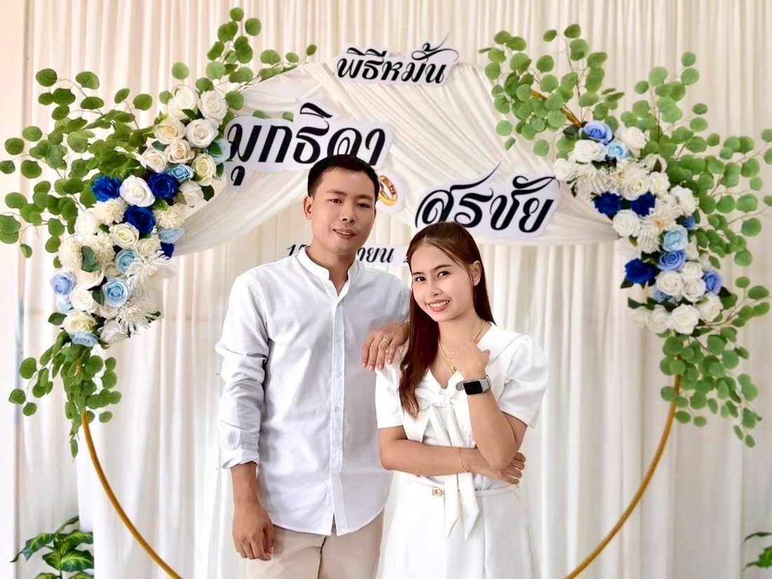 ยืนเคียงข้างกันหน้าซุ้มพิธี